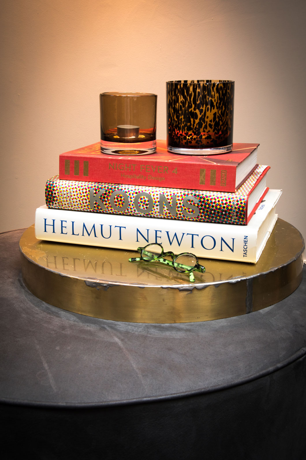 Smoke and leopard-spotted class votives sitting atop a stack of books.